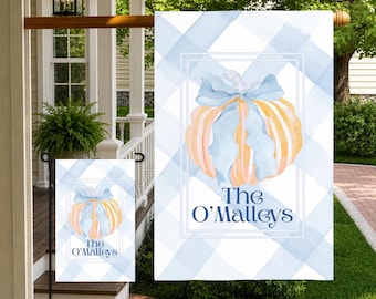 May include: A rectangular garden flag featuring a light blue and white watercolor plaid pattern. Centered is a pale orange pumpkin adorned with a light blue ribbon bow. Below the pumpkin, the text reads The O'Malleys in dark blue font.