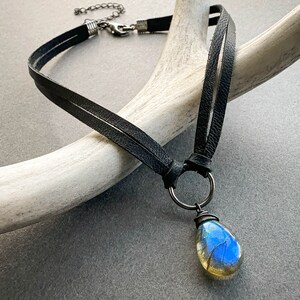 May include: A black leather choker necklace with a silver clasp and a teardrop-shaped labradorite pendant.