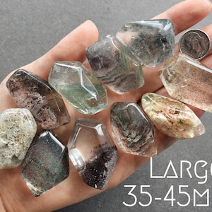 May include: A collection of nine green, brown, and white gemstone points. The points are all roughly the same size and shape, and they are arranged in a hand. The text "LARGE: 35-45MM" is visible in the image.