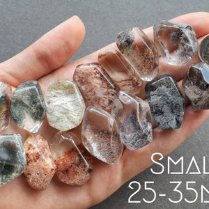 May include: A collection of 10 small, clear quartz crystals with inclusions of green, brown, and black. The crystals are in various shapes and sizes, ranging from 25 to 35 millimeters.  SMALL: 25-35MM
