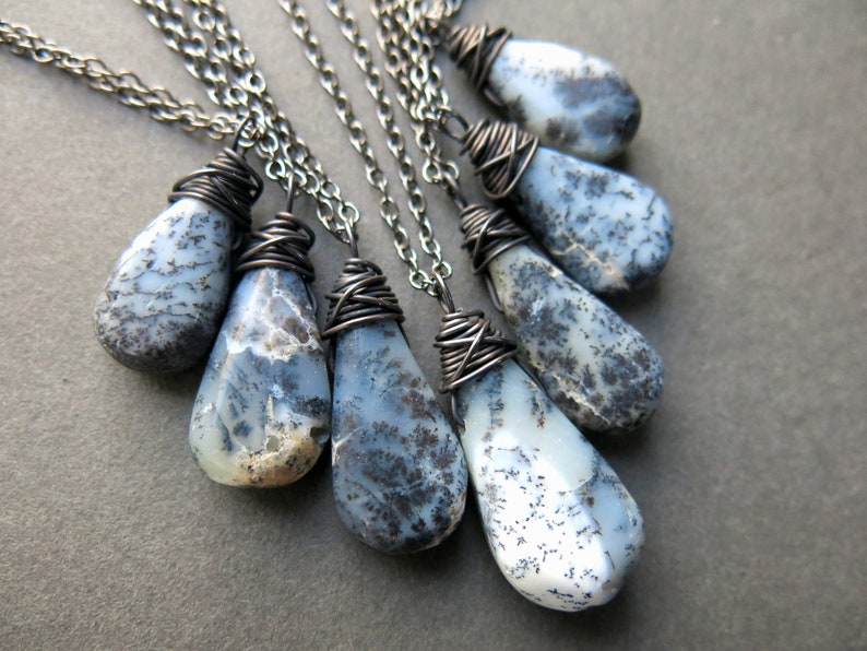May include: A set of seven silver necklaces with teardrop-shaped pendants made of blue and white agate. Each pendant is wrapped with silver wire.