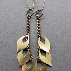 May include: A pair of long gold earrings with a chain and multiple leaf-shaped charms.