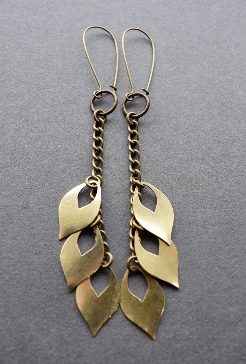 May include: A pair of long gold earrings with a chain and multiple leaf-shaped charms.