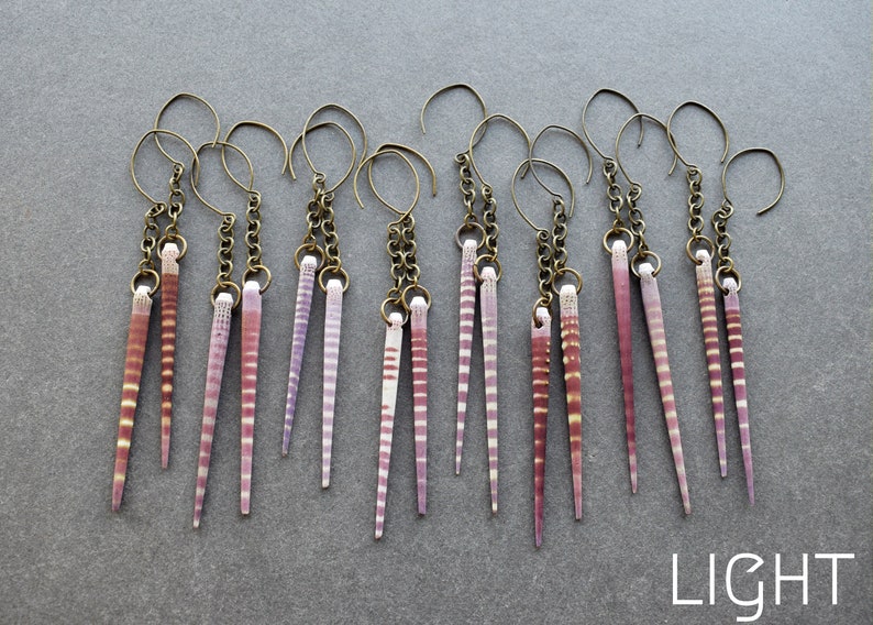 May include: A set of 10 earrings featuring pairs of long, thin, pink and white striped seashells hanging from gold chains.