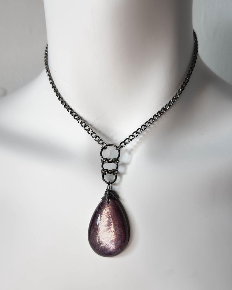 K&ouml;nnte beinhalten: Eine Halskette mit einer Kette aus Gunmetal mit einem tropfenf&ouml;rmigen Anh&auml;nger. Der Anh&auml;nger ist tiefviolett mit schillerndem Schimmer. Die Halskette hat eine Kette, drei Verbindungsringe und einen drahtumwickelten Anh&auml;nger.