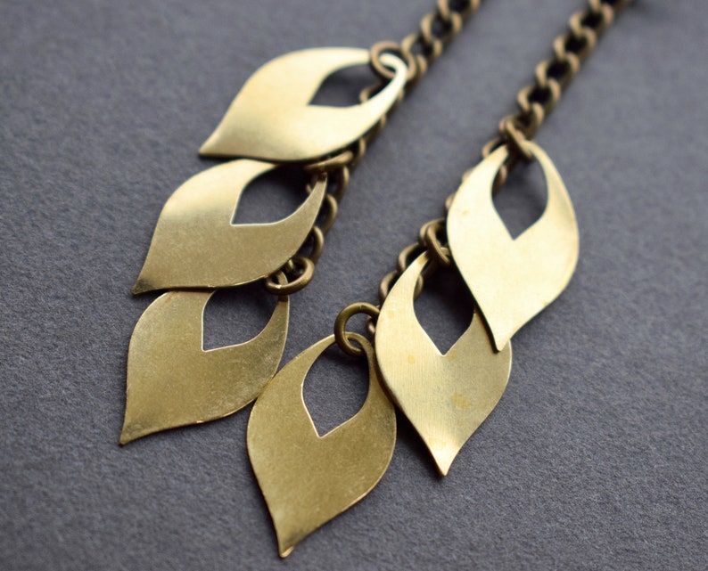 May include: Gold tone dangle earrings with a chain and multiple leaf-shaped charms.