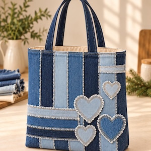 May include: A vertical tote bag constructed from patchwork denim strips in varying shades of blue. The bag features frayed edges along the seams and three heart-shaped denim appliqués in light and medium blue tones on the front panel.