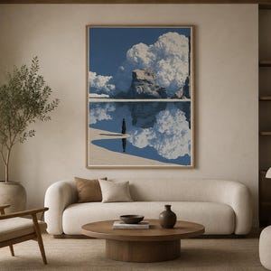 Könnte beinhalten: Ein gerahmter Kunstdruck mit einer surrealen Landschaft, die eine große Felsformation und flauschige weiße Wolken vor einem tiefblauen Himmel zeigt, gespiegelt in einem ruhigen Gewässer mit einer einsamen Figur am sandigen Ufer.