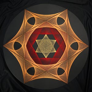 May include: A circular string art piece on a black base featuring a central golden six-pointed star surrounded by intricate geometric patterns. The design uses vibrant orange and red threads to create complex, layered curves and sharp angles.