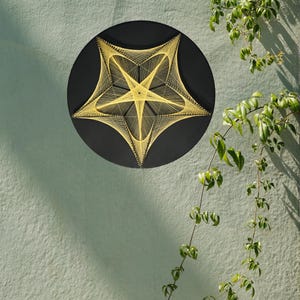May include: A circular wall art piece featuring a black background with a geometric star pattern created from yellow string. The design consists of intricate, intersecting lines that form a five-pointed star shape, anchored by small pins.