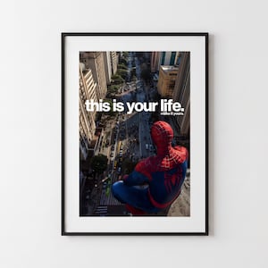 Könnte beinhalten: Ein gerahmtes Poster mit einer Ansicht aus der Vogelperspektive auf eine Stadtstraße, bei der eine rot-blau kostümierte Figur im Vordergrund auf einem Sims sitzt. Der Text "this is your life. make it yours." steht in Weiß über dem Stadtbild.