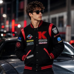 May include: A black varsity jacket with red leather sleeves and red striped ribbed trim. The jacket features various embroidered patches including a large red letter K, the text Kavinsky, Plasma, Renegade, Zombie, Horizon, Pulsar, Cameo, and Outsider.