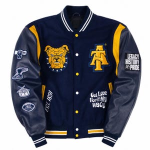 May include: A navy blue varsity jacket with yellow sleeves, featuring a bulldog patch, an AT logo, and text including EST. 1891 and Got Love For My HBCU. The sleeves have patches of a fist, a winged shoe, a drum, and a football, with LEGACY HISTORY PRIDE.