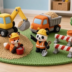 Op de afbeelding: Een gehaakte bouwset met een gele graafmachine, een oranje kiepwagen, twee groene bomen, twee rood-wit gestreepte barrières, twee oranje vaten, een vos met een gele helm en een panda met een helm en een veiligheidsvest.