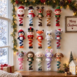 Op de afbeelding: Een verzameling van vijftien gehaakte kerstornamenten die in drie rijen hangen. De figuren omvatten een kerstman, sneeuwpop, rendier, peperkoekmannetje, elf, pinguïn, notenkraker, vos, uil, kat, muis, egel, schaap, konijn en hond.