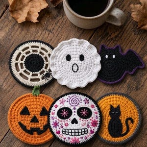 Pode incluir: Um conjunto de seis bases para copos em crochê com temas de Halloween: uma teia de aranha preta e branca, um fantasma branco, um morcego preto, uma abóbora laranja, uma caveira branca com detalhes florais e um círculo com um gato.