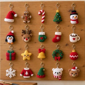 Puede incluir: Un tablero de madera con veinte adornos navideños de ganchillo colgados de ganchos metálicos. La colección incluye un gorro de Papá Noel, un hombre de jengibre, un bastón de caramelo, un árbol, un muñeco de nieve, un pingüino, un reno, una manopla, un calcetín, una taza, un regalo, una estrella, una campana, una corona, una bola, un copo de nieve, un suéter, un gorro de elfo, un oso polar y un osito de peluche.