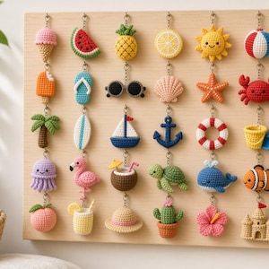 May include: A collection of thirty small, colorful crochet keychains arranged in a grid on a light wood board. The items feature various summer-themed shapes including fruits, sea creatures, beach accessories, and plants in vibrant yarn colors.