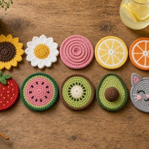 May include: A collection of ten round crochet coasters featuring various designs including a sunflower, daisy, pink circle, lemon slice, orange slice, strawberry, watermelon slice, kiwi slice, avocado half, and a grey cat face with pink ears.