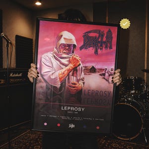 Puede incluir: Un póster enmarcado con la portada del álbum Leprosy de Death. La imagen muestra una figura encapuchada en un paisaje rosado con el logo de la banda arriba a la derecha. El texto dice Leprosy, Death 1988 y enumera los títulos de las canciones.