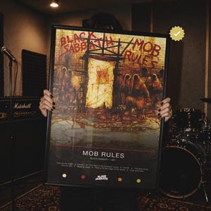 May include: A framed Black Sabbath Mob Rules poster featuring a dark, textured illustration of hooded figures before a glowing doorway. The text reads Black Sabbath Mob Rules, with a tracklist including Turn Up the Night and Over and Over.