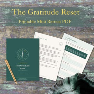 Peut inclure: Un PDF imprimable intitulé The Gratitude Reset, comprenant une couverture vert foncé avec un graphique de boussole, une page de lettre et une page intitulée The Honest Pause avec des invites d'écriture. Un stylo doré repose sur le document.