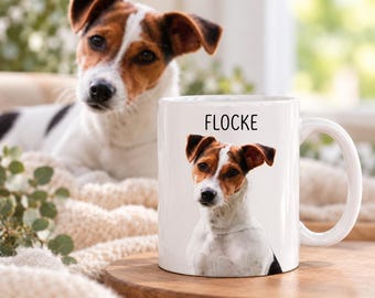 May include: A white ceramic mug featuring a photographic print of a Jack Russell Terrier with brown and white markings. Above the dog image, the name FLOCKE is printed in a simple black sans-serif font. The mug has a standard handle.