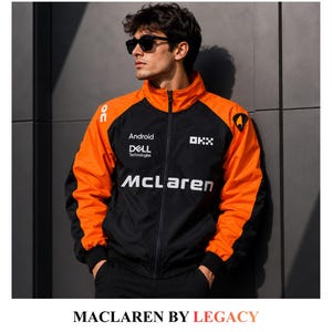 Può includere: Una giacca nera e arancione con cerniera che presenta il logo McLaren e i marchi Android, Dell Technologies e OKX. La giacca ha un colletto alto, maniche lunghe con polsini neri e un design a blocchi di colore con spalle arancioni e pannelli neri.