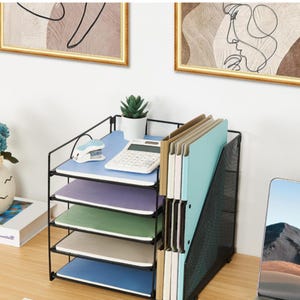 Peut inclure: Un organisateur de bureau en métal noir doté de cinq étagères horizontales et d'un porte-documents vertical. Les étagères contiennent des carnets empilés bleus, violets, verts et blancs, avec une calculatrice blanche et une petite plante grasse.