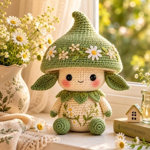 May include: A crochet mushroom doll with a green cap featuring white daisy embroidery, a cream-colored body with floral stitching, pink cheeks, and green leaf-shaped ears. The doll has a small smile and round black eyes, with green feet.