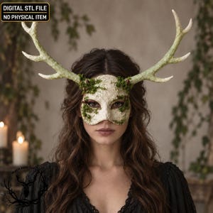 Pode incluir: Uma máscara de baile texturizada em tom branco sujo com grandes chifres de veado ramificados e manchas de musgo verde. A máscara inclui o texto DIGITAL STL FILE NO PHYSICAL ITEM. Este item foi projetado para cobrir a área dos olhos.