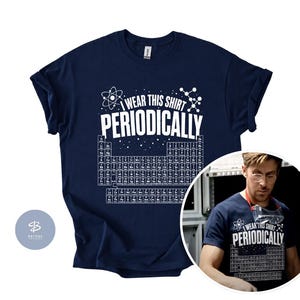 Peut inclure: Un t-shirt bleu marine à manches courtes arborant un graphique blanc du tableau périodique des éléments et le texte "I WEAR THIS SHIRT PERIODICALLY" avec des illustrations d'atomes et de molécules centré sur la poitrine du vêtement.