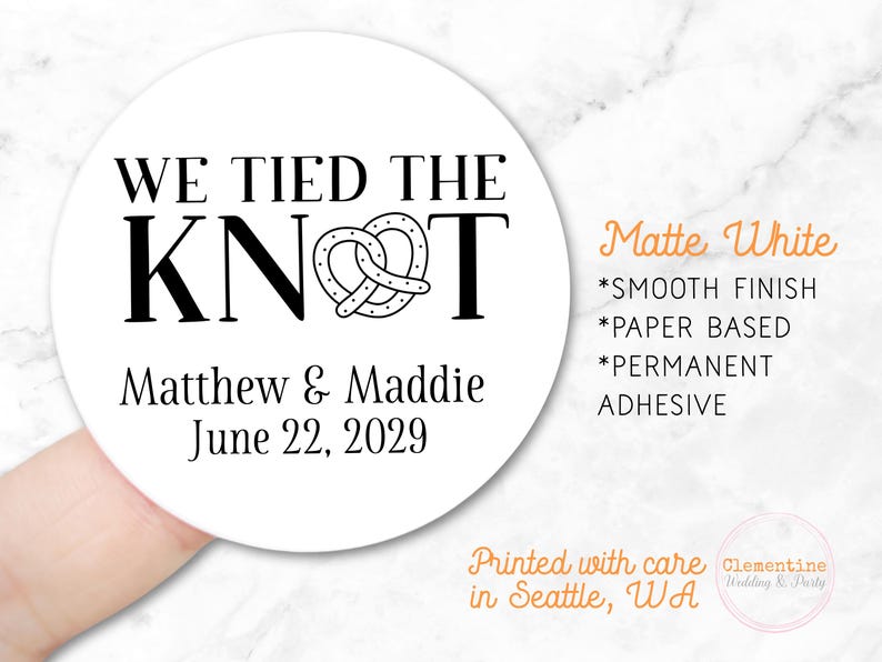 Round label is shown stuck on a fingertip.  Overlay text: ‘Matte White: Smooth finish, paper based, permanent adhesive. Printed with care in Seattle WA by Clementine Wedding & Party.'