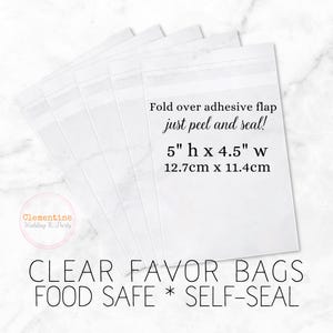 5 clear favor bags are fanned out on a white marble background.  Overlay text:  “CLEAR FAVOR BAGS * FOOD SAFE * SELF SEAL, 5”h x 4.5”w, 12.7cm x 11.4cm. Fold over adhesive flap - just peel and seal!”
