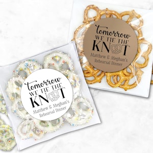 May include: Two clear cellophane bags filled with pretzels. One bag contains white chocolate-covered pretzels with colorful sprinkles, and the other contains traditional pretzels. Both bags have a circular sticker that reads "Tomorrow WE TIE THE KNOT" and the names "Matthew & Meghan's Rehearsal Dinner."