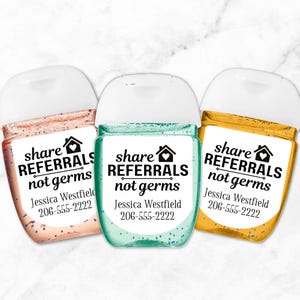 Three small bottles of hand sanitizer with white labels that say "share referrals not germs" and include a phone number and name. The bottles are peach, teal, and yellow.