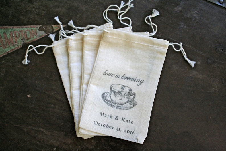 May include: Set of five white cotton drawstring bags with a black and white illustration of a teacup and the text "love is brewing" printed on the front. The bags also include the text "Mark & Kate" and "October 31, 2016".