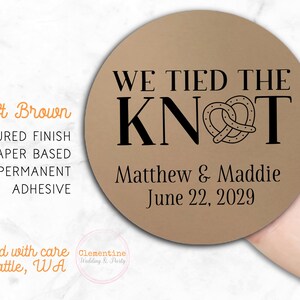 Round label is shown stuck on a fingertip.  Overlay text: 'Kraft Brown: Textured finish, paper based, permanent adhesive. Printed with care in Seattle WA by Clementine Wedding & Party.'