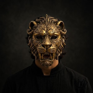 May include: A metallic gold lion mask featuring intricate swirling patterns across the forehead and cheeks. The mask displays a fierce expression with bared teeth, a prominent nose, and a detailed mane that frames the face, covering the eyes.