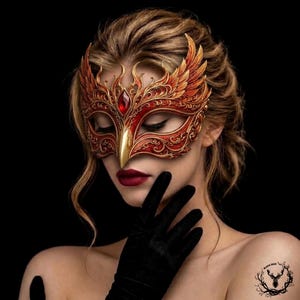 May include: An ornate masquerade mask featuring intricate filigree patterns in shades of red and gold, accented with a central red gemstone and wing-like side details. The mask covers the upper face, showcasing a pointed nose bridge and deep red lips.