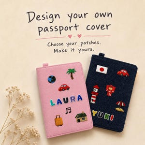 May include: Two passport covers, one pink and one dark blue, featuring embroidered patches. The pink cover displays the name LAURA with patches of a globe, palm tree, car, music note, suitcase, and house. The blue cover displays YUKI with patches of a flag, car, lighthouse, kimono, and umbrella.