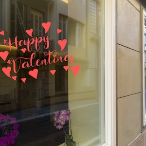 May include: A storefront window with a red "Happy Valentine's" message with hearts surrounding the text. The window is reflecting the street outside.