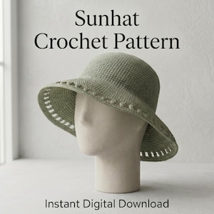 May include: A sage green crochet sunhat displayed on a mannequin head. The hat features a textured crown, a row of small bobble stitches along the brim, and a decorative openwork pattern at the edge. Text reads: Sunhat Crochet Pattern. Instant Digital Download.
