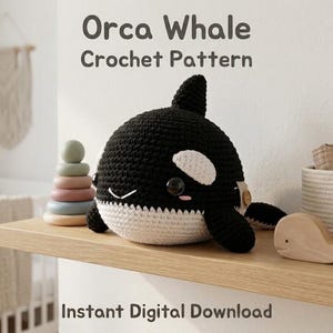 May include: A black and white crocheted orca whale plush toy with large black eyes, pink cheek accents, and a small wooden button on the side. The text Orca Whale Crochet Pattern and Instant Digital Download is visible in the image.