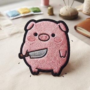 May include: An embroidered patch featuring a round, pink pig character with small black eyes and rosy cheeks. The pig is holding a silver-colored knife with a brown handle in its right hand. The entire design is outlined with a thick black border.