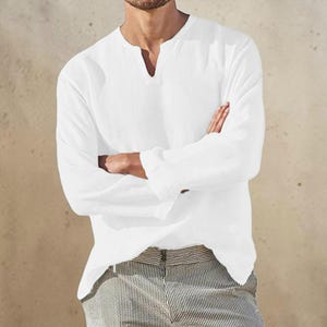 Peut inclure: Une chemise blanche &agrave; manches longues avec une encolure fendue et une finition en tissu textur&eacute;. La chemise pr&eacute;sente une coupe d&eacute;contract&eacute;e avec des manches droites et une couleur blanche unie, associ&eacute;e &agrave; un pantalon ray&eacute; clair.