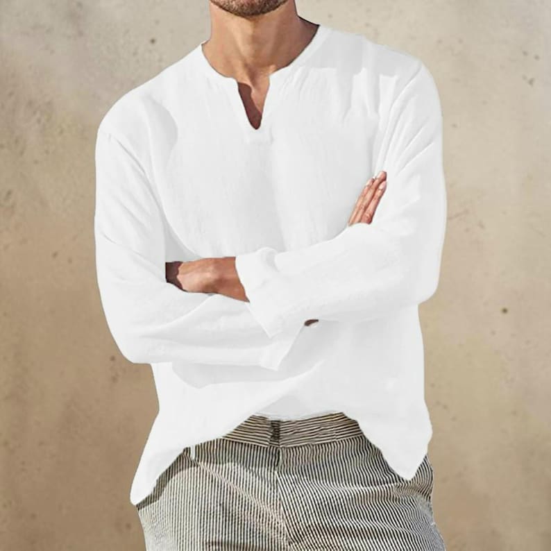 Peut inclure: Une chemise blanche &agrave; manches longues avec une encolure fendue et une finition en tissu textur&eacute;. La chemise pr&eacute;sente une coupe d&eacute;contract&eacute;e avec des manches droites et une couleur blanche unie, associ&eacute;e &agrave; un pantalon ray&eacute; clair.