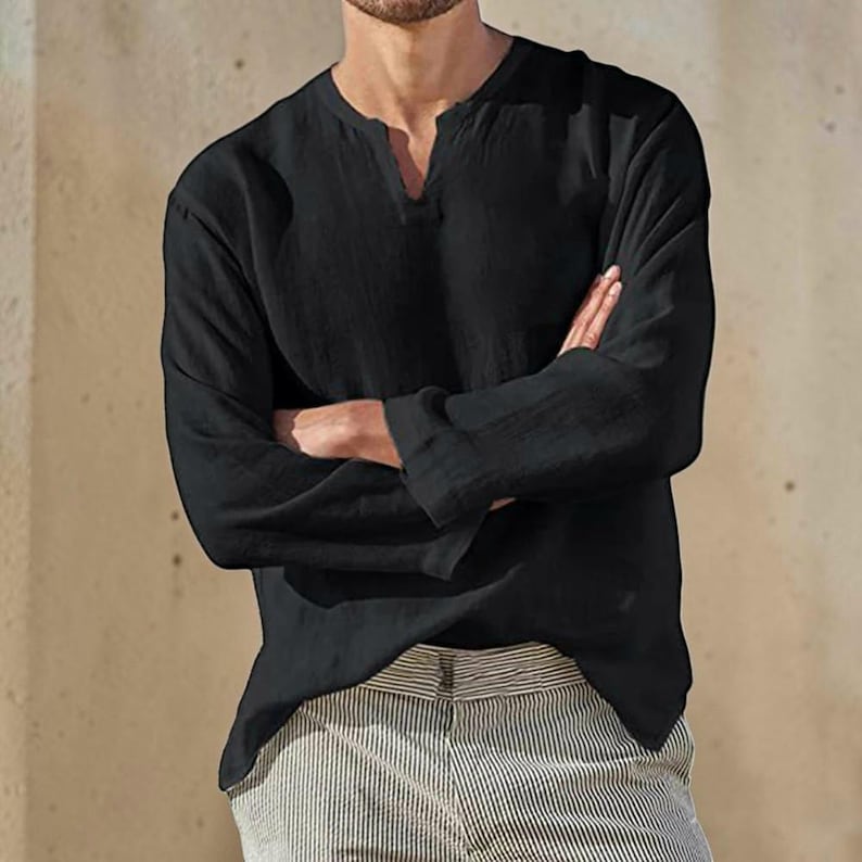 Peut inclure: Une chemise noire &agrave; manches longues avec une petite ouverture en col en V et une finition en tissu textur&eacute;, associ&eacute;e &agrave; un pantalon clair pr&eacute;sentant un motif &agrave; rayures verticales subtil. La chemise a une coupe d&eacute;contract&eacute;e avec des poignets.