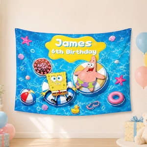 May include: A rectangular blue fabric backdrop featuring a water-themed pattern with Spongebob Squarepants and Patrick Star floating in inner tubes. The text James 6th Birthday is printed in white on a yellow cloud shape. Includes beach balls and shells.