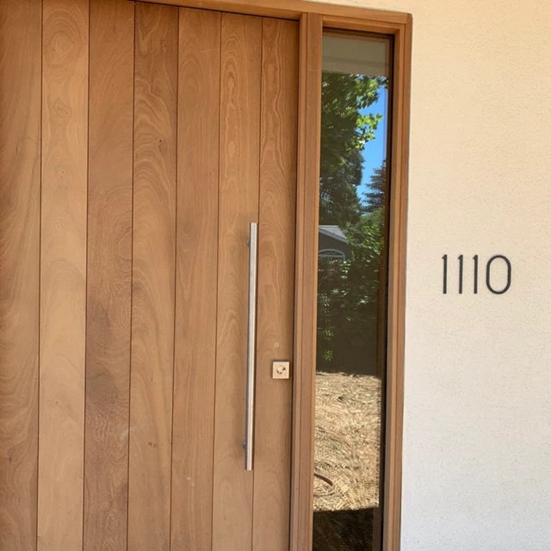 May include: A wooden door with a silver handle and a glass window pane. The house number 1110 is visible on the wall.